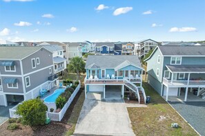 A residential area with houses featuring balconies, a swimming pool, and a driveway. - "Pirate Pride" a Charming 3 Bedroom, 2 Bathroom, Dunes Home! (Holden Beach)