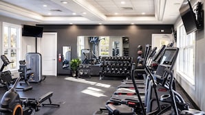 Ein Fitnessstudio mit Laufbändern, Kraftgeräten und Kurzhanteln.