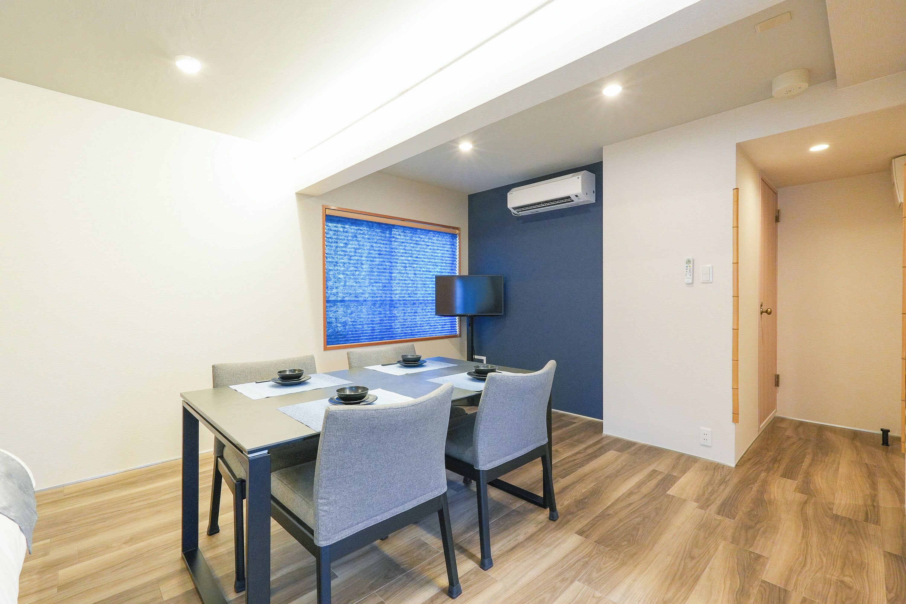 A dining area with a table, chairs, and a window with blinds.