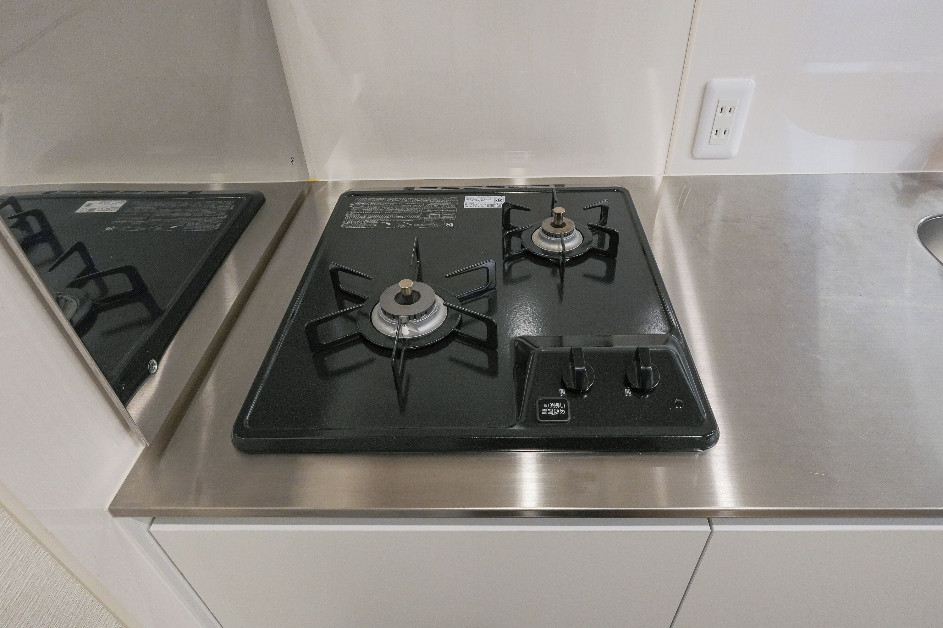 A kitchen with a stainless steel countertop, two gas stoves, and a sink.