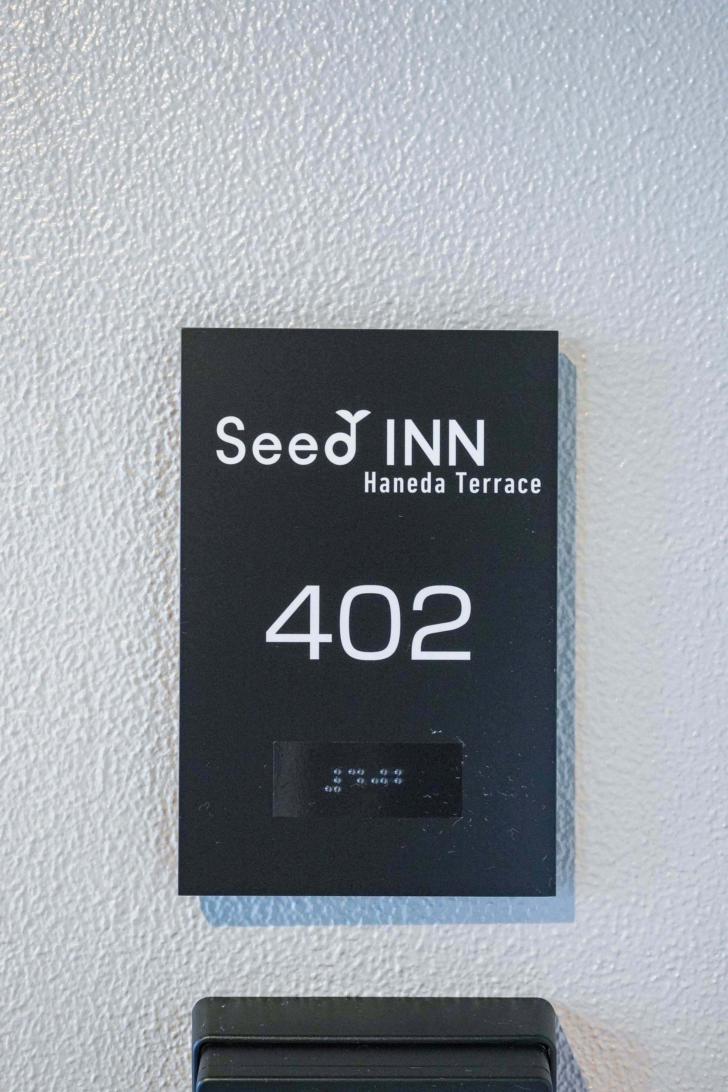 A black sign with 'Seed Inn' and '402' on a textured wall.