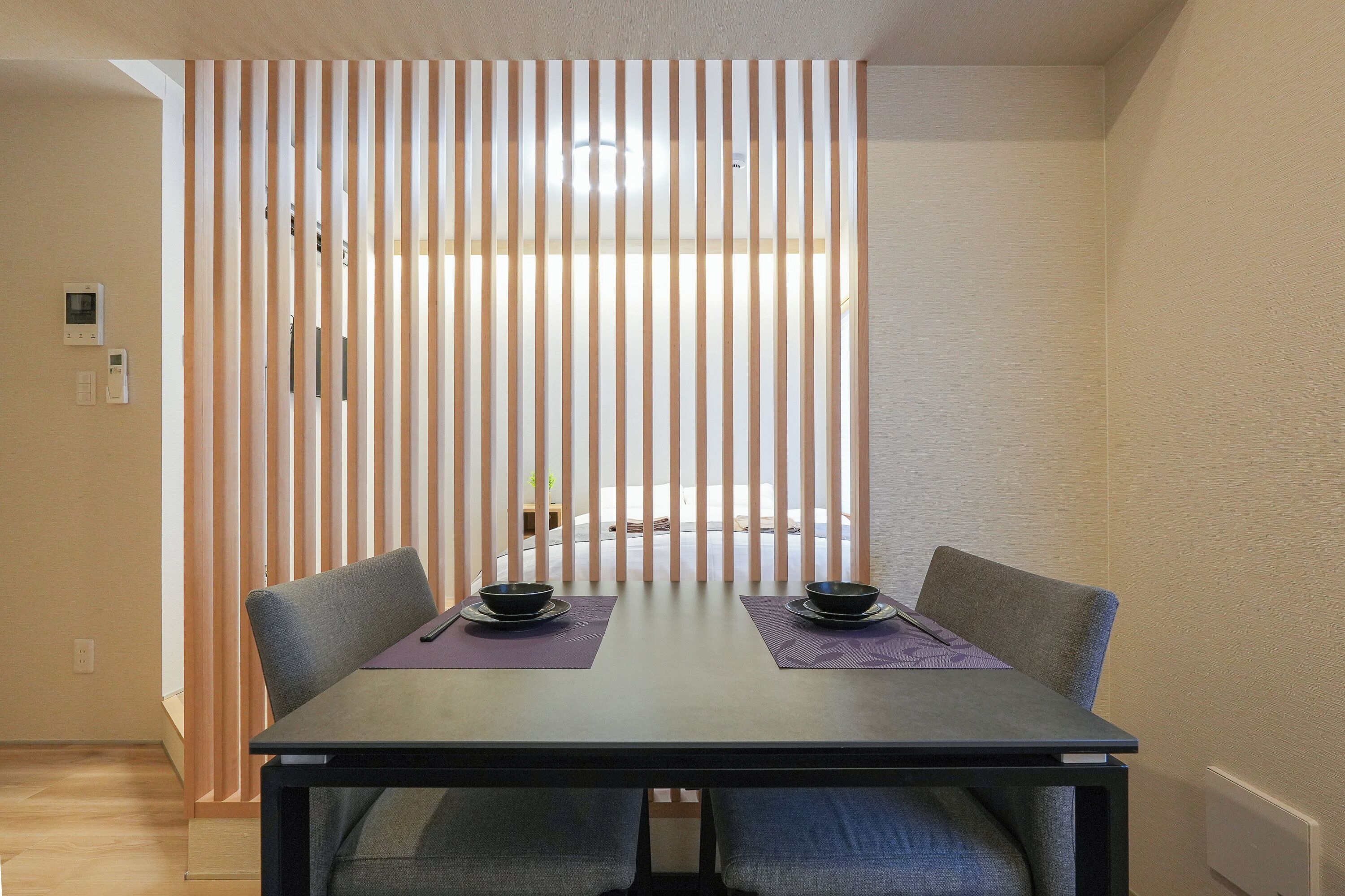 A dining area with a table, chairs, and a partition with vertical slats.