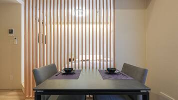 A dining area with a table, chairs, and a partition with vertical slats.