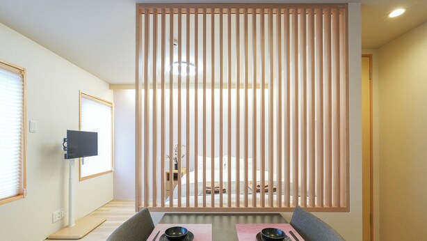 A dining area with a table set for two, a television on a stand, and a sliding door with vertical blinds. - Seed INN Haneda Terrace (Tokyo)