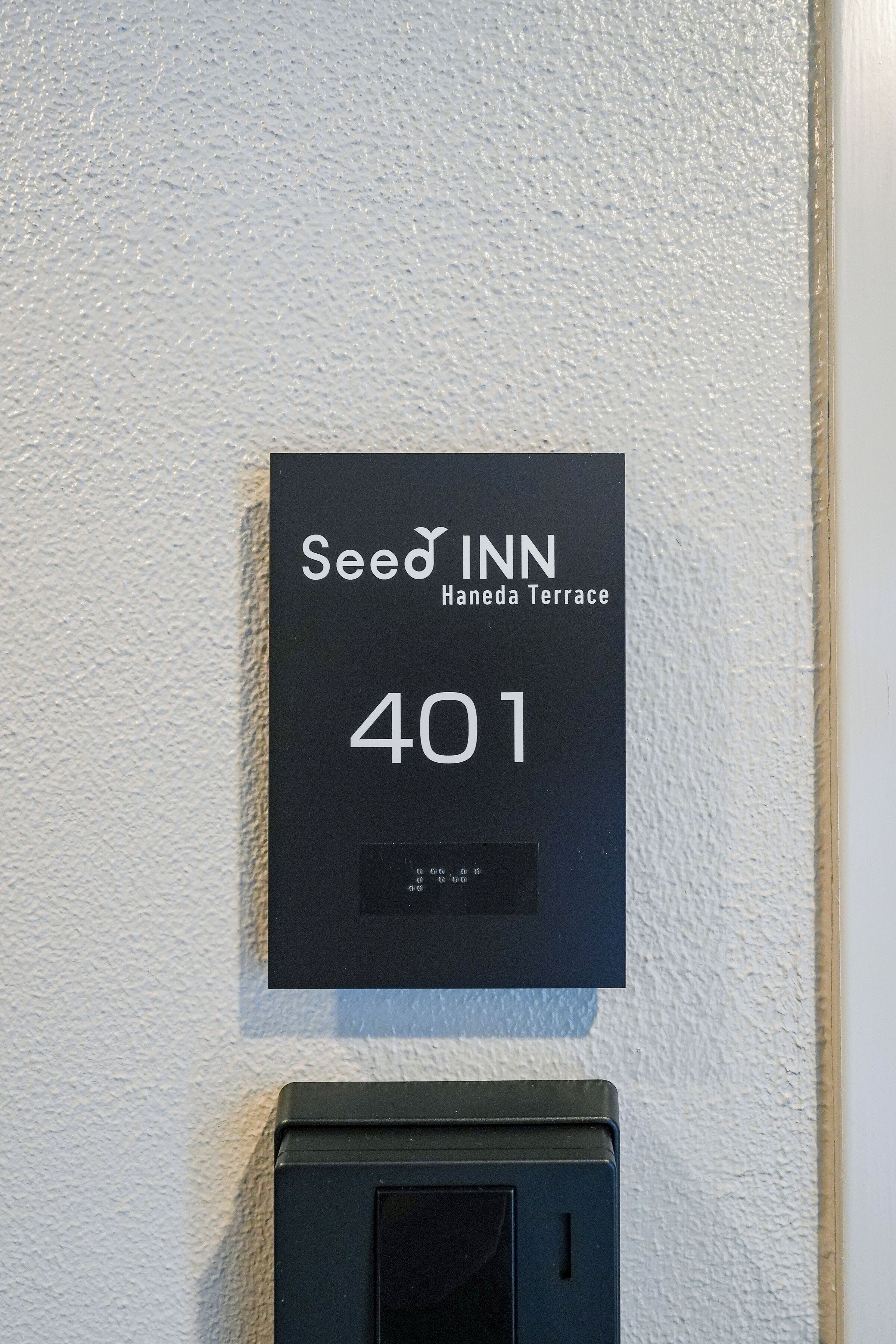 A black sign with white text indicating 'Seed Inn Haneda Terrace 401.'