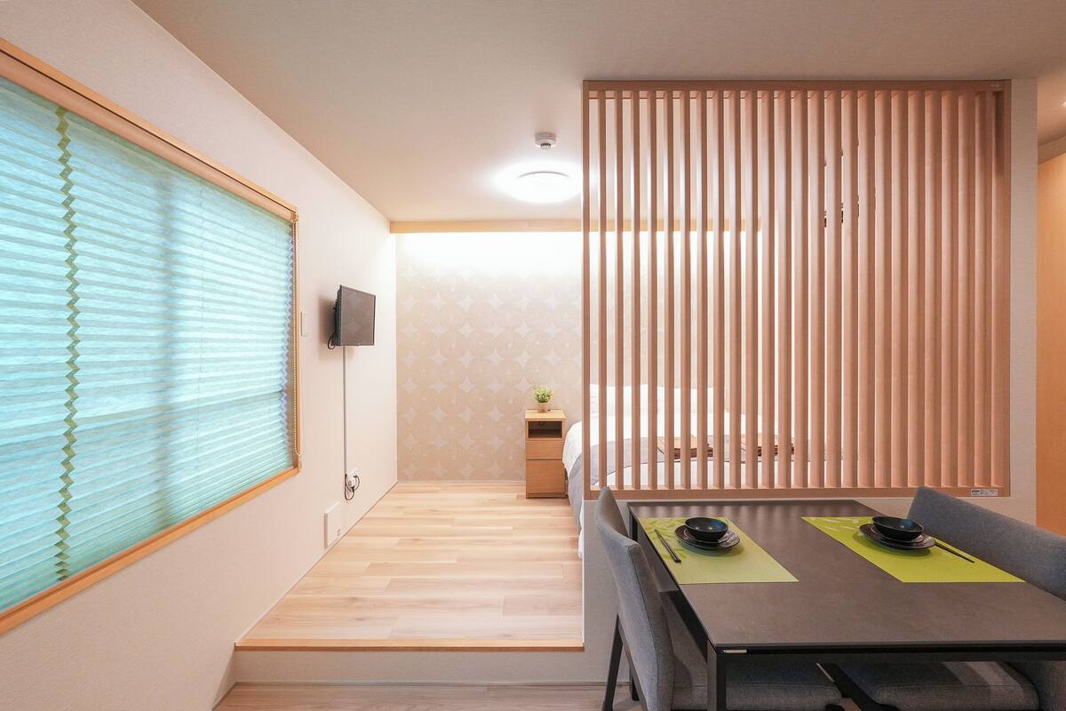 A modern dining area with a wooden table, chairs, and a television mounted on the wall.