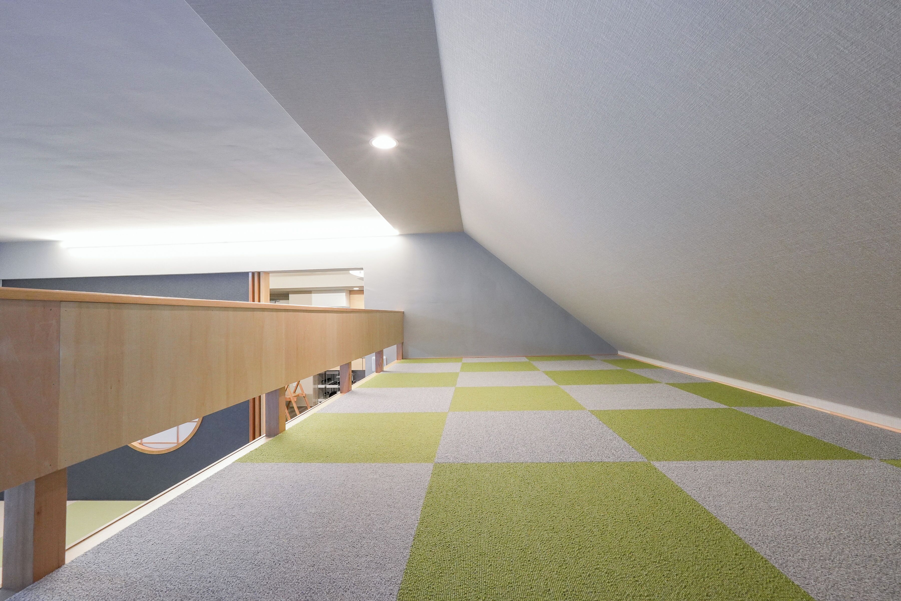 Un interior moderno con techo inclinado, un banco de madera y alfombra de cuadros.