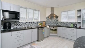 Uma cozinha moderna com armários brancos, micro-ondas, fogão e painel de azulejos.