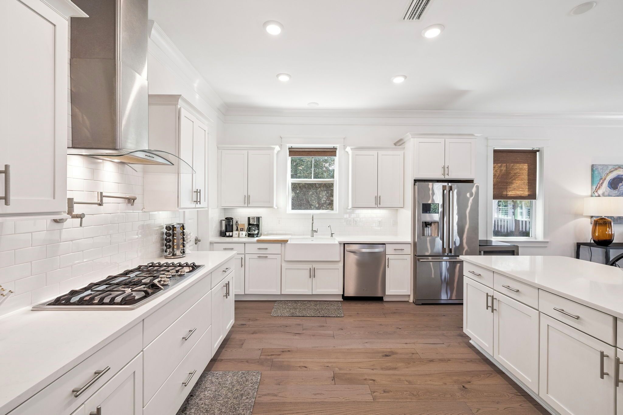 Una cocina moderna con armarios blancos, electrodomésticos de acero inoxidable y piso de madera.