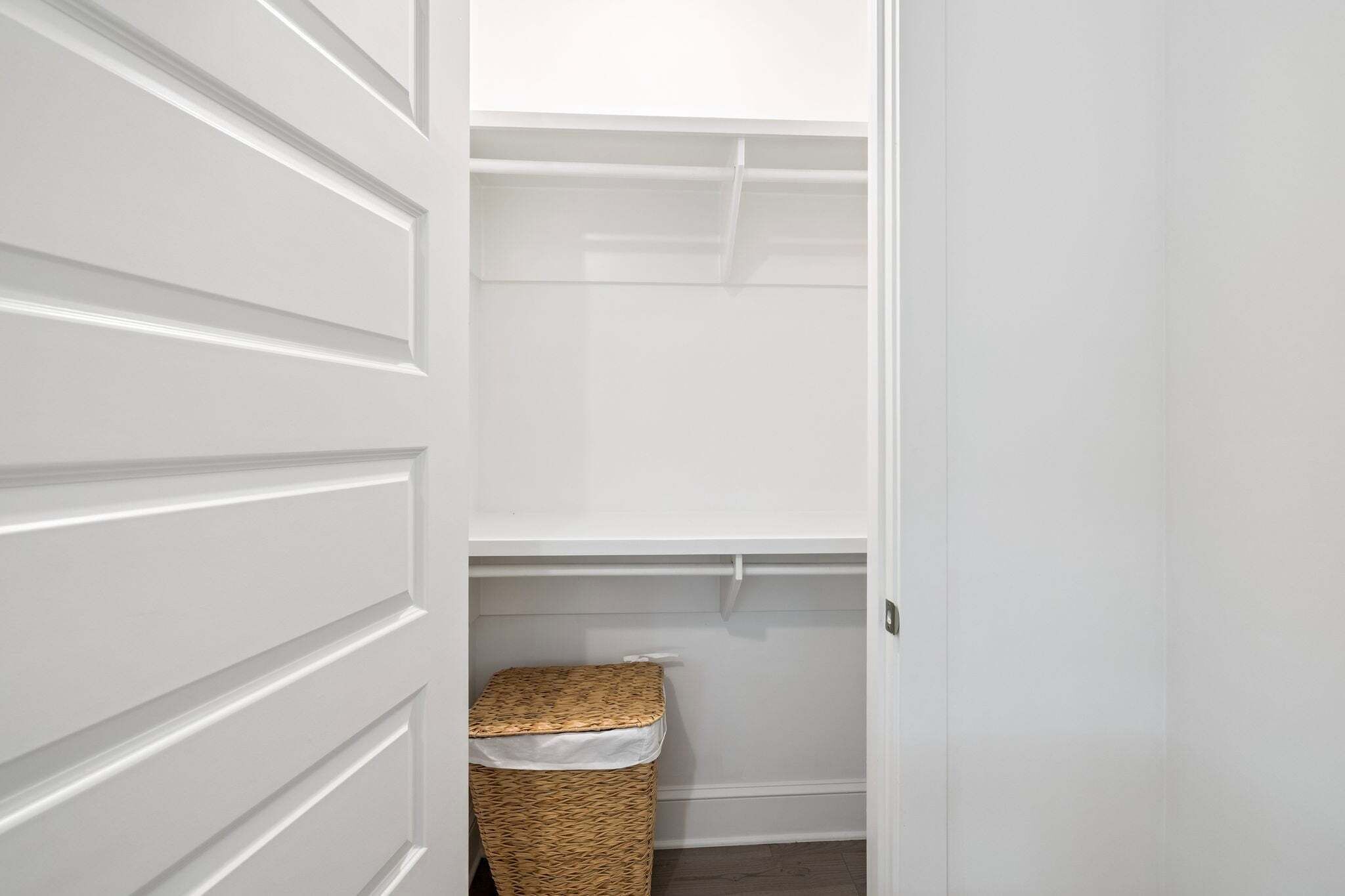 A white closet with shelves and a wicker basket.
