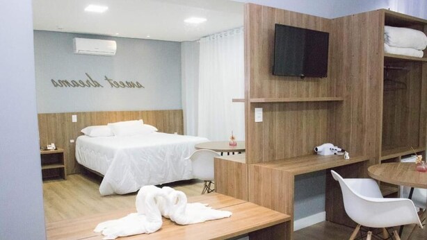 Une chambre d’hôtel moderne équipée d’un lit, d’un bureau, d’une chaise et d’un téléviseur fixé au mur.