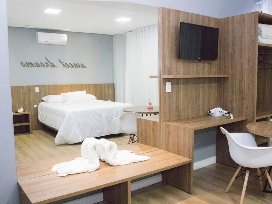 Ein modernes Hotelzimmer mit Bett, Schreibtisch, Stuhl und einem an der Wand befestigten Fernseher.