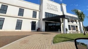 Un hôtel moderne à la façade sobre, doté de grandes fenêtres et d’une enseigne indiquant « HÔTEL ALBORADA ».