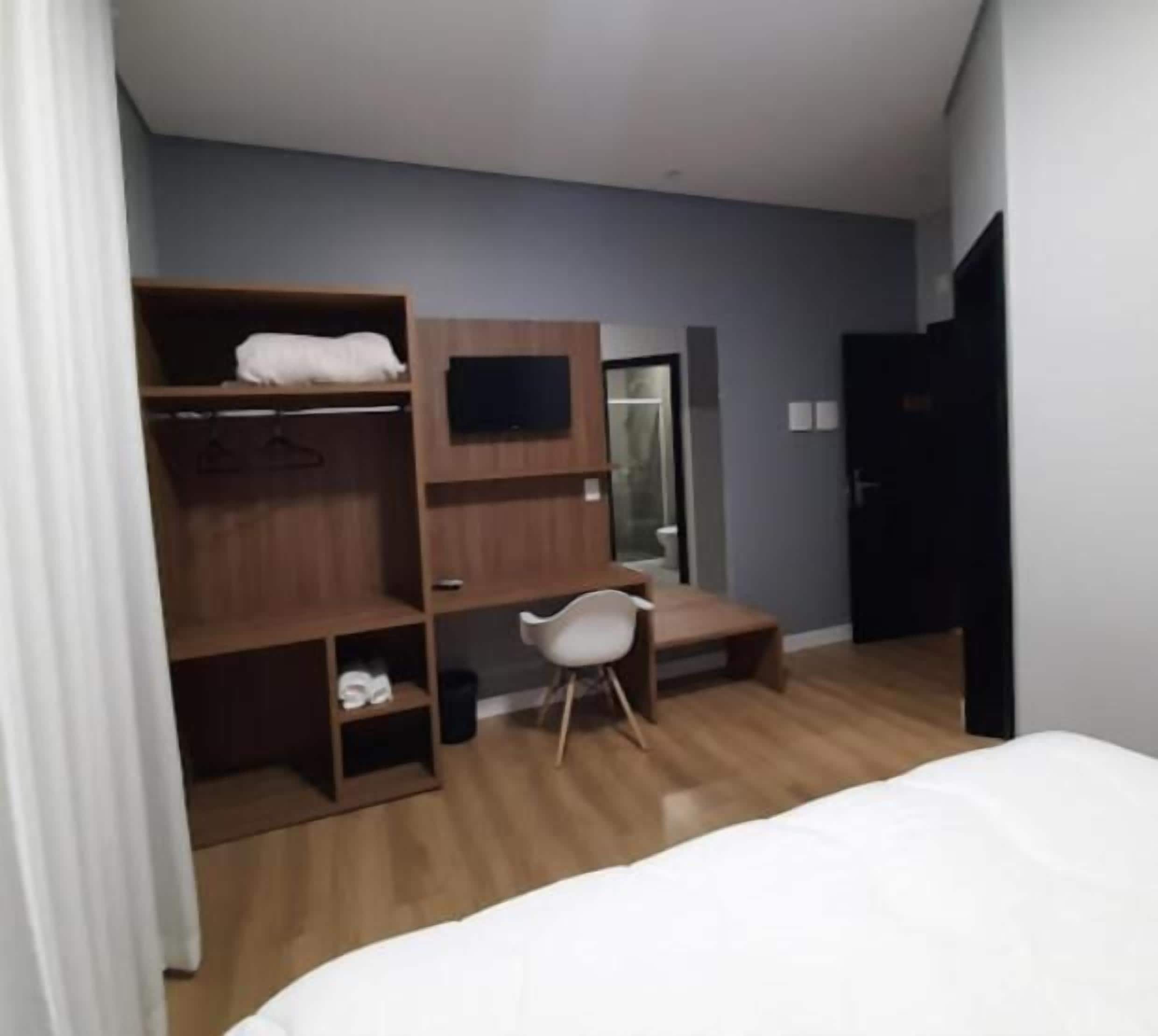 Une chambre avec un lit superposé, un bureau, une chaise et une armoire.