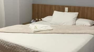 Una cama bien hecha con sábanas blancas, un cabecero de madera y un aire acondicionado instalado en la pared.