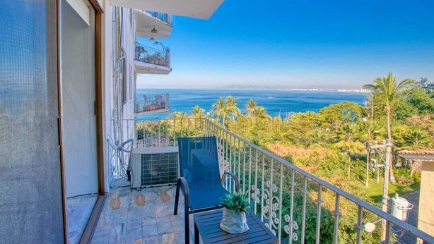 Een balkon met uitzicht op zee, een stoel en een kleine tafel.