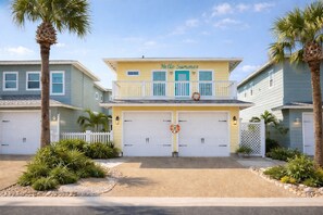 A two-story house with a yellow facade, a balcony, and a garage with two doors. - VW21 Shared Heated Pools, Charcoal Grill, Gated Community (Port Aransas)