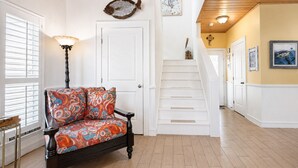 Un couloir doté d’un plancher en bois, d’un banc avec un coussin à motifs, d’un escalier et d’un mur décoré de motifs représentant des poissons.