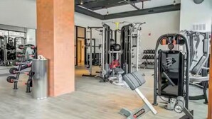 A gym with various exercise equipment, a mirrored wall, and a wooden floor.