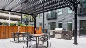 An outdoor patio with a table and chairs, a grill, and a covered seating area.