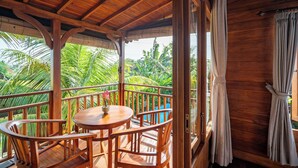 A wooden deck with a round table and chairs, surrounded by lush tropical foliage. - Aris Villa Ubud (Ubud)