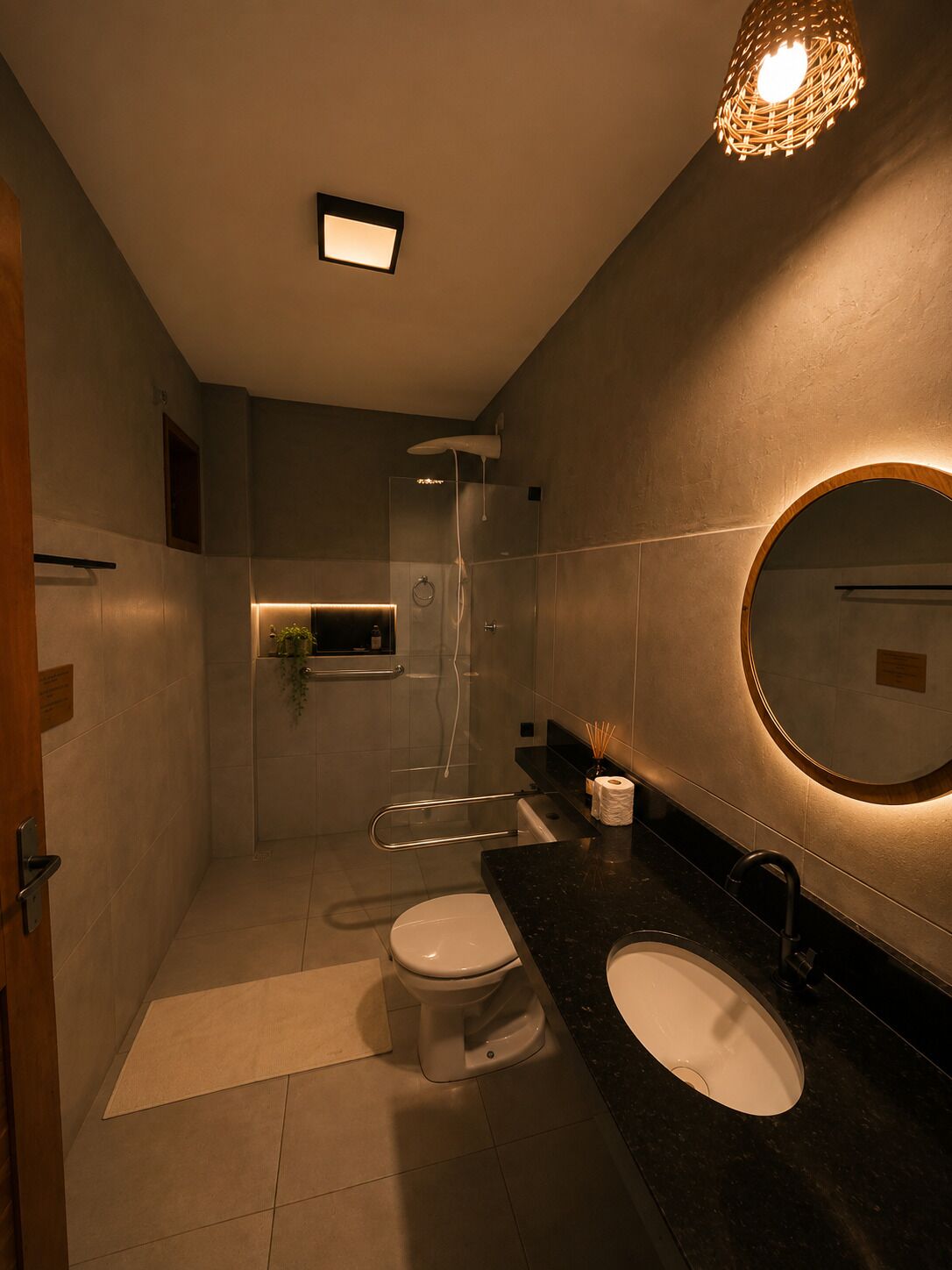 A modern bathroom with a glass shower enclosure, a round mirror, and a dual sink vanity.