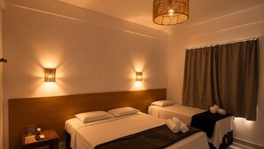 Une chambre d’hôtel avec deux lits, une table de chevet, une lampe et un luminaire suspendu.