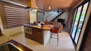 Una cocina moderna con una isla central, horno empotrado y zona de comedor con taburetes de bar.