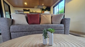 Una sala de estar moderna con un sofá gris, una mesa de centro de madera con una planta y un techo de madera.