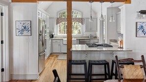 Una cocina amplia con vigas de madera, armarios blancos y una isla central.