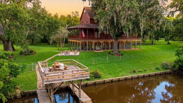 A wooden house with a porch, a dock, and a lawn. - Riverfront, HotTub, BoatRamp, Deck, Sleeps 24 (West Columbia)