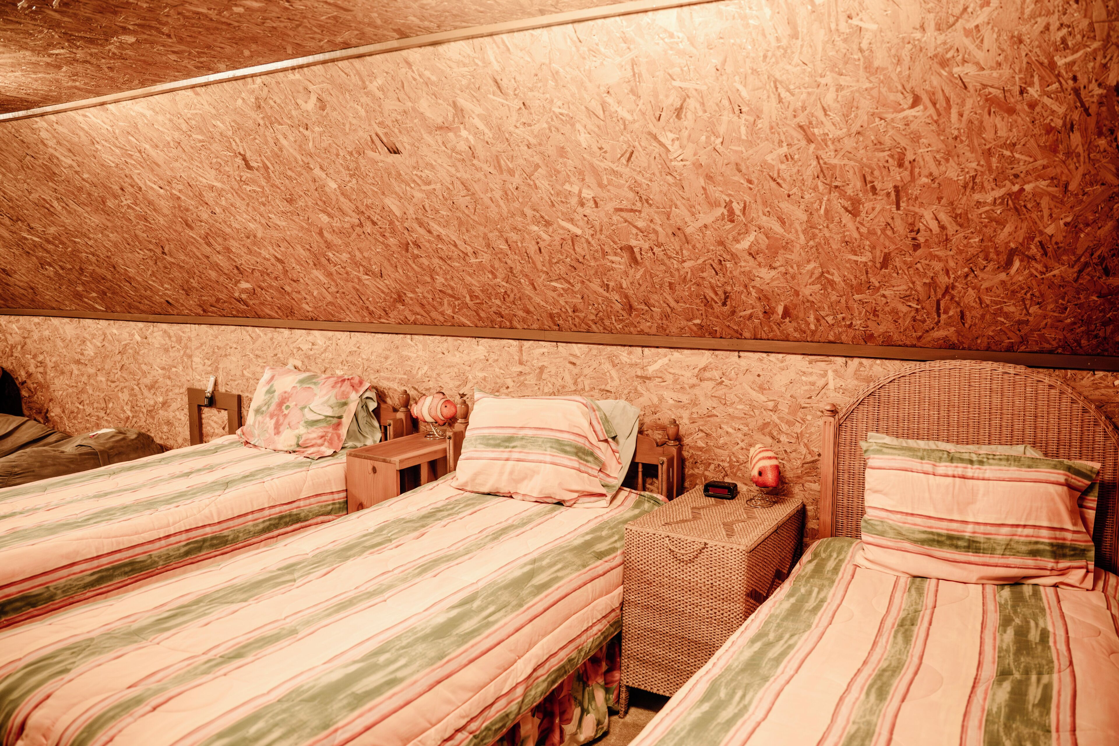 A bedroom with two beds, a wooden ceiling, and a wicker headboard.