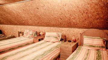 A bedroom with two beds, a wooden ceiling, and a wicker headboard.
