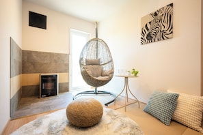 Ein modernes Wohnzimmer mit einem Hängekorbsessel, einem kleinen Tisch mit Pflanze und einem Zebra-Kunstwerk an der Wand.