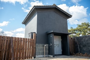 A building with a dark facade, a gated entrance, and a visible door.
