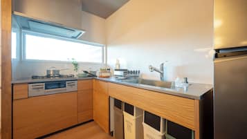 A modern kitchen with wooden cabinets, a stainless steel refrigerator, and a window providing natural light.