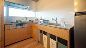 Eine moderne Küche mit Holzausstattung, einem Edelstahlkühlschrank und einem Fenster für natürliches Licht.
