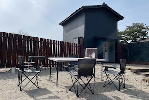 An outdoor patio with a table and chairs, a wooden fence, and a building in the background.