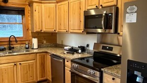 Una cocina moderna con armarios de madera, electrodomésticos de acero inoxidable, encimeras de granito y un microondas integrado.