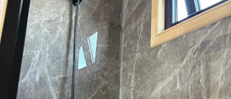 Une douche équipée d’un pommeau de douche à main et d’un flexible à main.