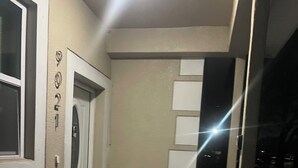 Un couloir étroit, avec une porte sur la gauche et une rangée de placards sur la droite.