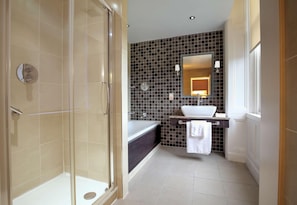 Een moderne badkamer met een douchecabine van glas, een donkere betegelde muur, een witte wastafel en een grote spiegel.