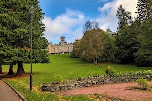 A building with a tower, surrounded by trees and a stone wall. - Doubletree by Hilton Dunblane Hydro (Dunblane)