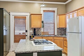 Eine Küche mit Granit Arbeitsplatten, Holzschränken, einem Gasherd und einem Kühlschrank.