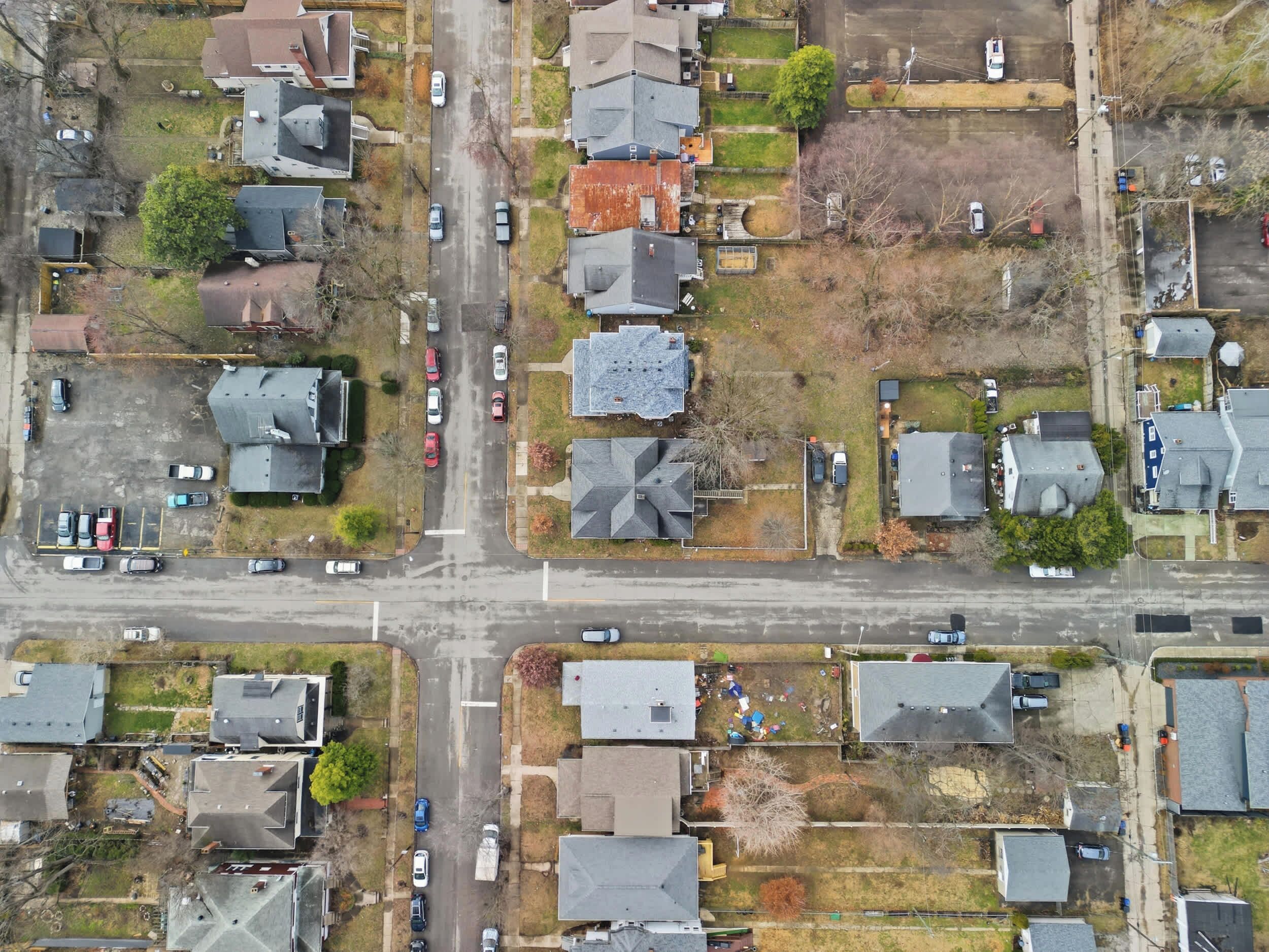 Vue aérienne d’un quartier résidentiel avec des maisons, des rues et des voitures garées.