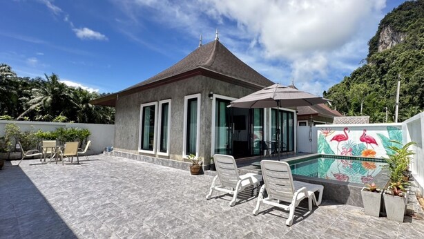 A building with a tiled patio, outdoor seating, and a swimming pool with a decorative tile mural. - The Star Aonang Private Pool Villa -  Aonang Krabi with 2 bedrooms (Mueang Krabi)