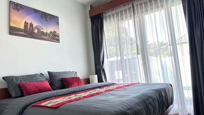 A bedroom with a large bed, dark curtains, a painting of a scenic view, and a wooden ceiling. - The Star Aonang Private Pool Villa -  Aonang Krabi with 2 bedrooms (Mueang Krabi)