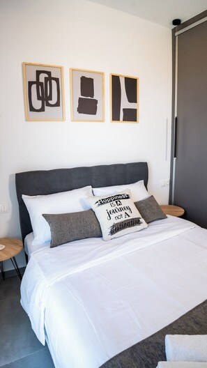 A bedroom with a bed, pillows, a bedside table, and a wardrobe.