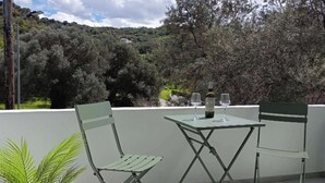 A balcony with two green chairs and a table, a bottle of wine, and two glasses. - Basil Leaf - Minimal View Retreat (Gonia)