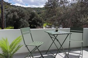 Ein Balkon mit zwei grünen Stühlen und einem Tisch, einer Weinflasche und zwei Gläsern.